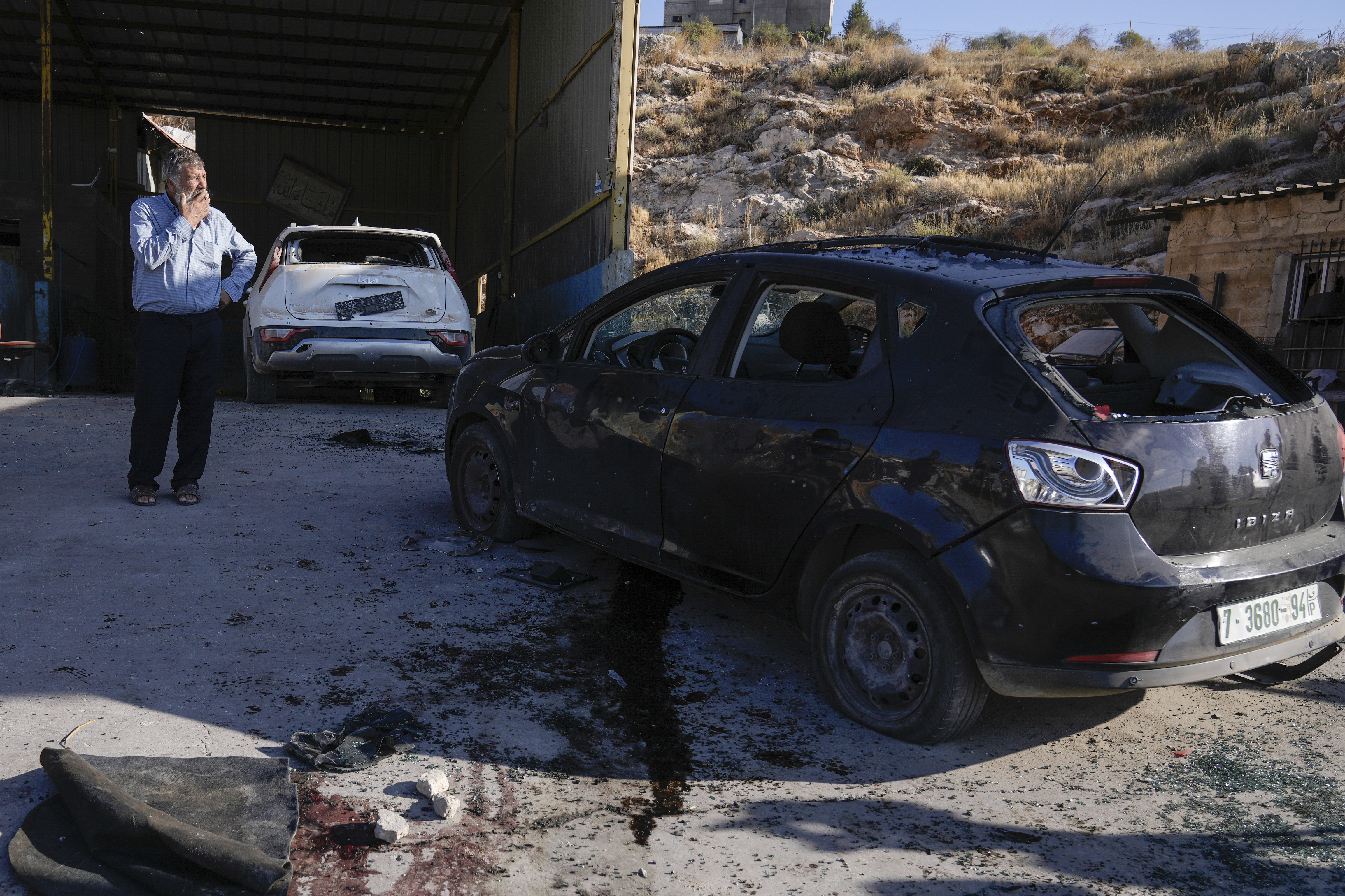 Palestinians look at a damaged car following an Israeli airstrike in Tubas, West Bank, Thursday, Sept. 5, 2024. Palestinian health officials say Israeli strikes in the occupied West Bank killed five people. Israel has been carrying out large-scale raids in the territory over the past week that it says are aimed at dismantling militant groups and preventing attacks. (AP Photo/Majdi Mohammed)