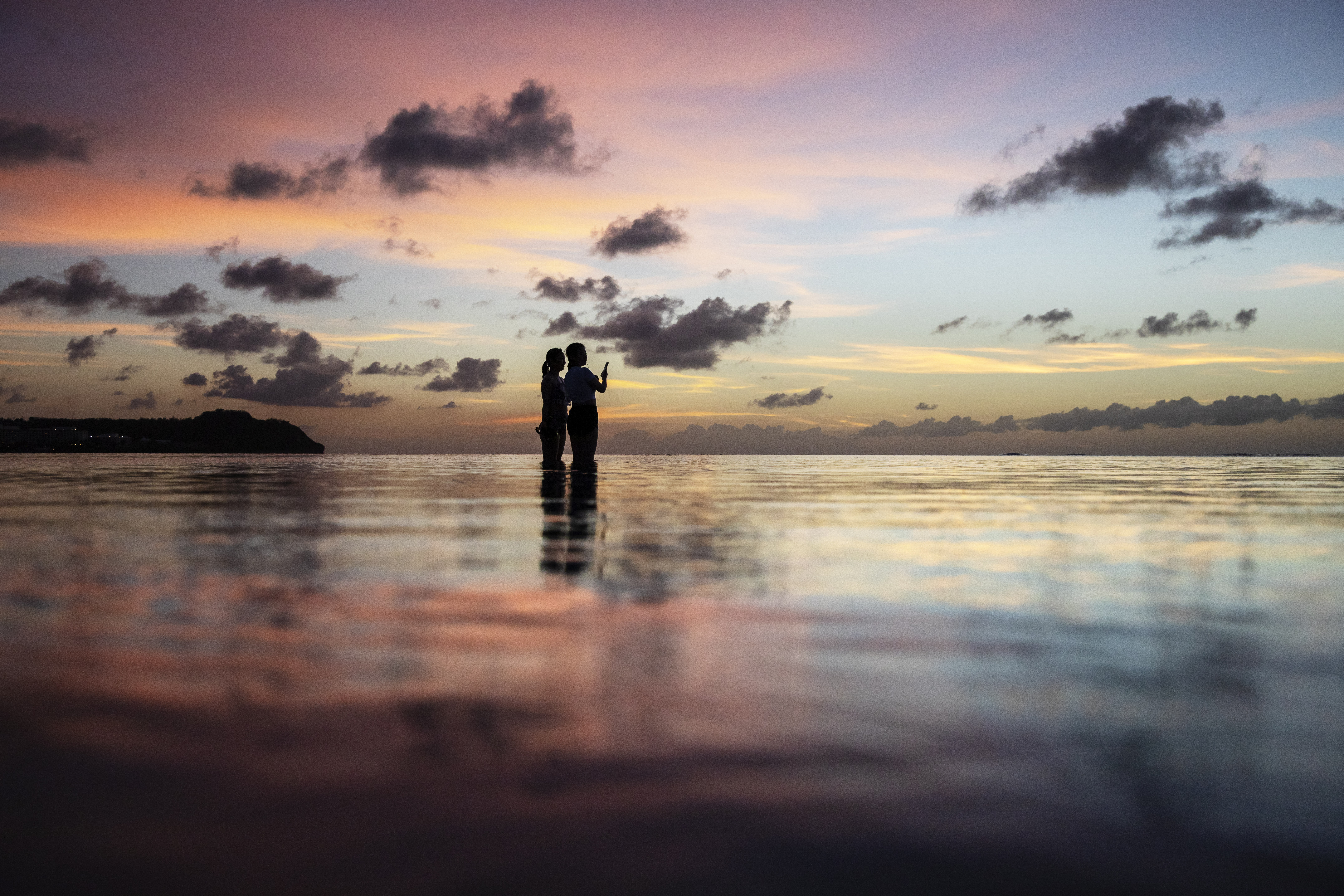 FILE - Tourists watch the sun set along a popular beach in Tamuning, Guam, May 6, 2019. (AP Photo/David Goldman, File)