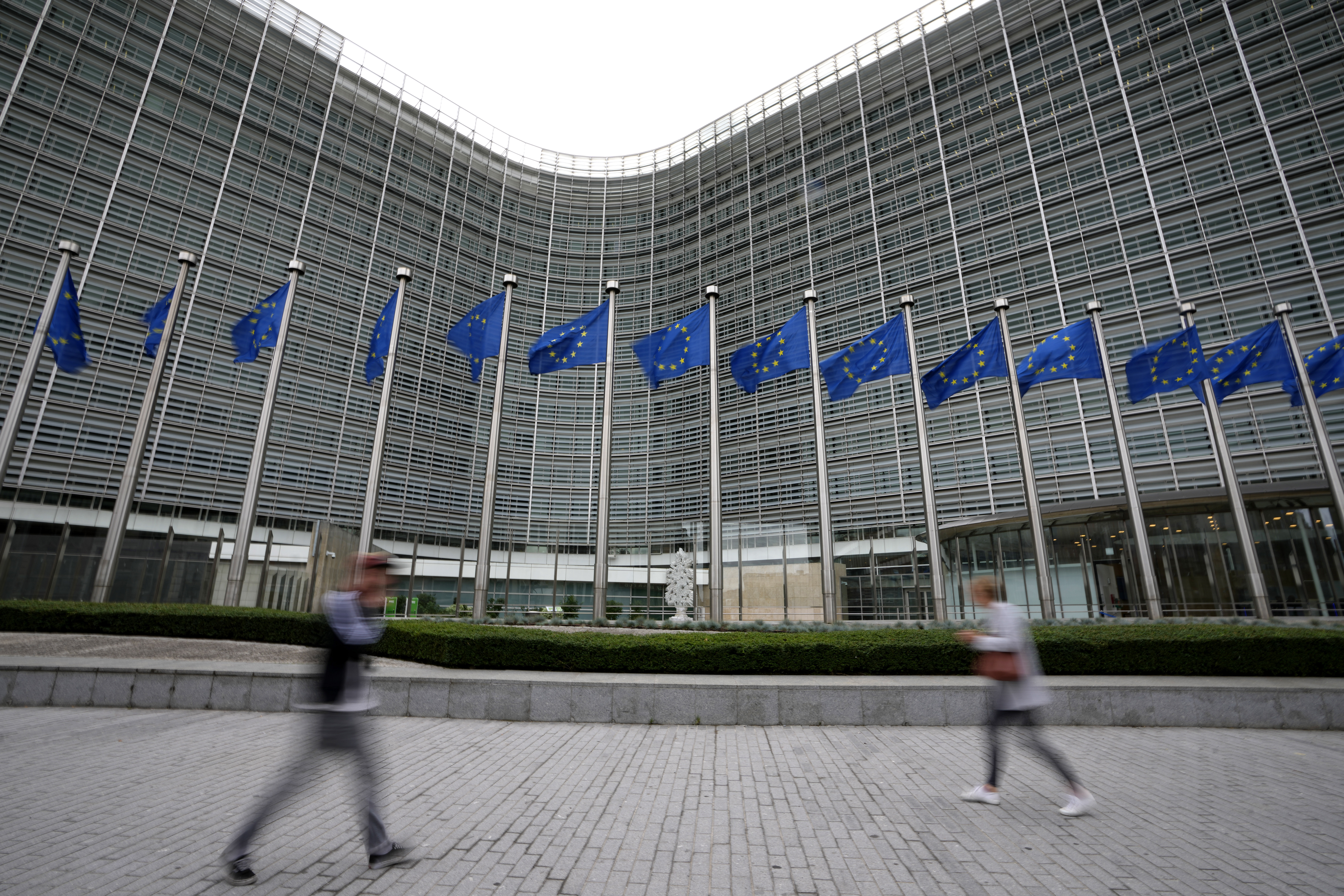 CORRECT THE NAME OF THE WEBSITE - FILE - European Union flags wave in the wind as pedestrians walk by EU headquarters in Brussels, on Sept. 20, 2023. The European Union said Wednesday July 10, 2024 it's adding the porn site XNXX to its list of online services facing the strictest level of scrutiny under the bloc's digital regulations including measures requiring users to verify their ages. (AP Photo/Virginia Mayo, File)