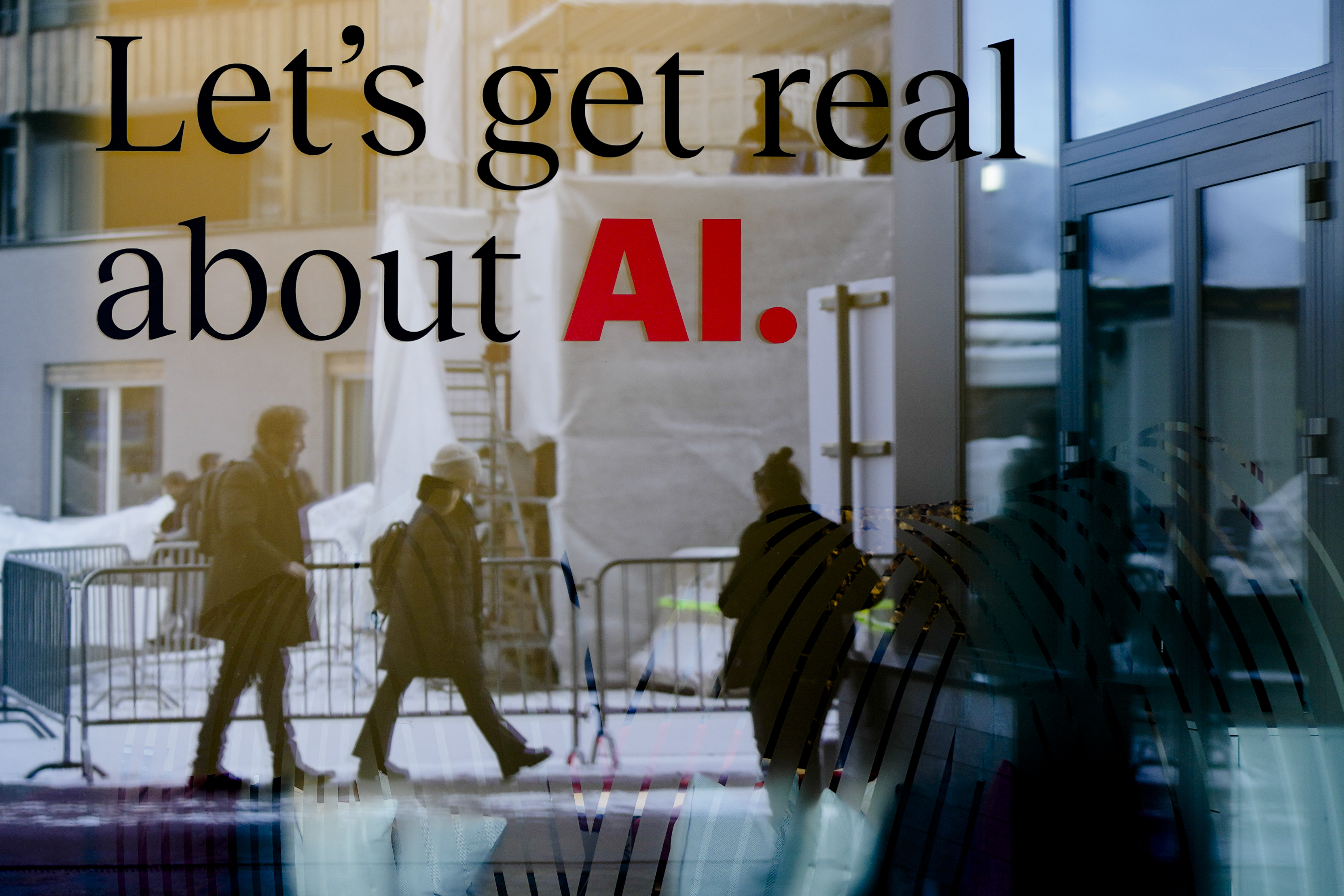 FILE - People are reflected in a window of a hotel at the Davos Promenade in Davos, Switzerland, Jan. 15, 2024. The artificial intelligence startup Perplexity AI has raised tens of millions of dollars from the likes of Jeff Bezos and other prominent tech investors for its mission to rival Google in the business of searching for information. (AP Photo/Markus Schreiber, File)