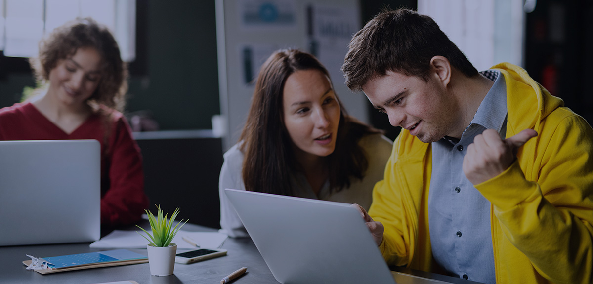 people sitting at a laptop, talking and smiling