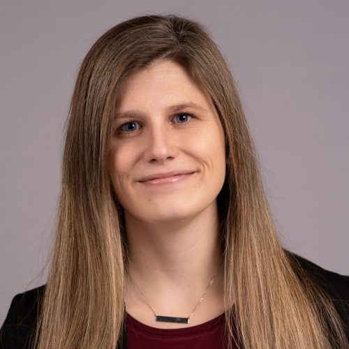 Kristin Handley is a young White woman with brown hair. She smiles wearing a silver necklace, dark red blouse and black sweater.