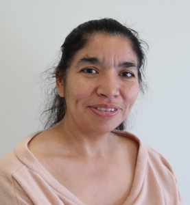 Susana Barrios is a Latino woman with long black hair. She smiles wearing a light pink v-neck sweater.