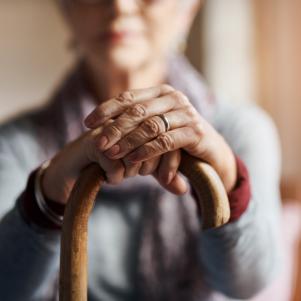 Cropped shot of a senior woman holding a cane in a retirement home