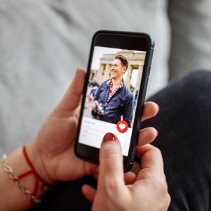 Close-up of a female using a dating app on smart phone. Woman looking at man on an online dating app on her mobile phone.