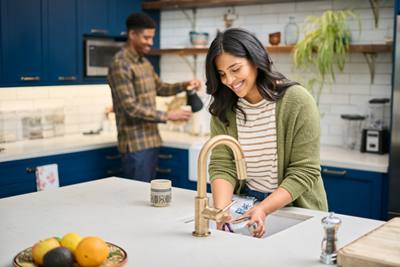 Woman doing dishes while husband pours a cup of coffee in the kitchen