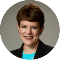 Headshot of Teresa Fraker, FACHE, RN, CPHQ, CBN, with short brown hair, wearing a black blazer, with a gray background