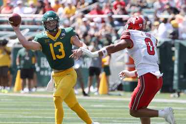 Baylor quarterback Sawyer Robertson throws on the run as Utah defensive end Logan Fano...