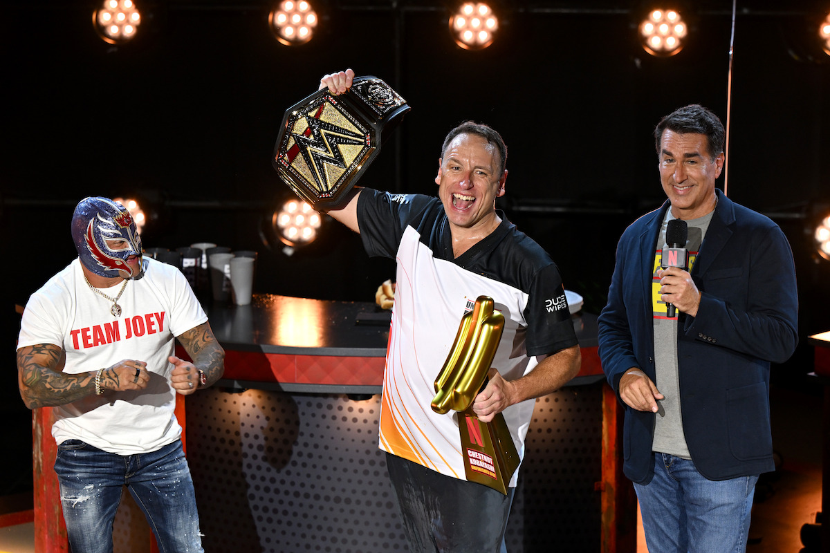 Rey Mysterio, Joey Chestnut, and Rob Riggle on stage.