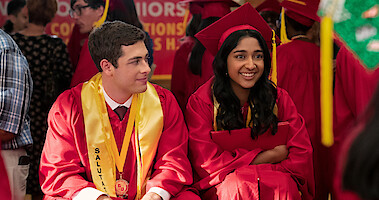 Jaren Lewison as Ben Gross and Maitreyi Ramakrishnan as Devi in Never Have I Ever Season 4 sitting at graduation.