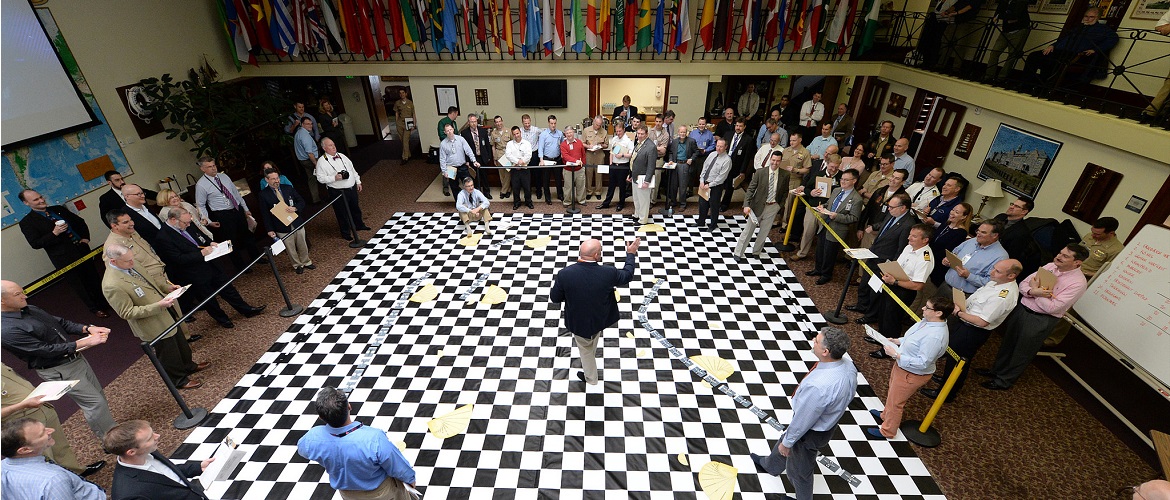 U.S. Naval War College (NWC) staff members listen to a brief during a wargame reenactment of the Battle of Jutland at NWC in Newport, Rhode Island.