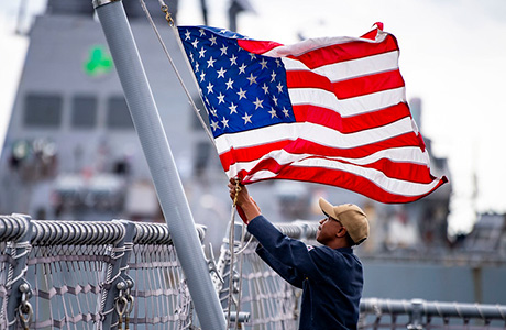 A Sailor assigned to the Freedom-class variant littoral combat ship USS Billings (LCS 15) lowers the American flag.