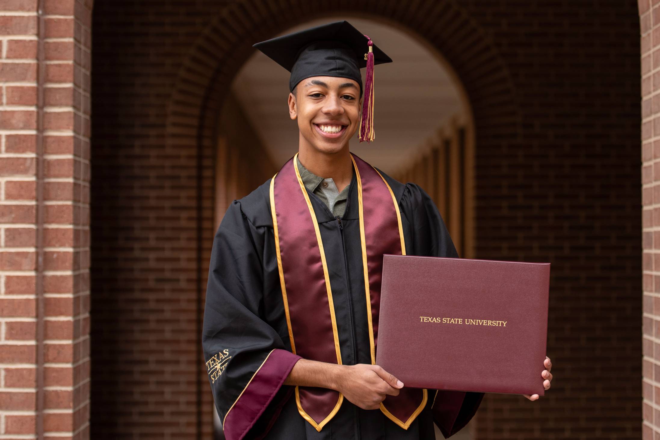 Classic bachelor's degree robes in black with maroon and gold accents