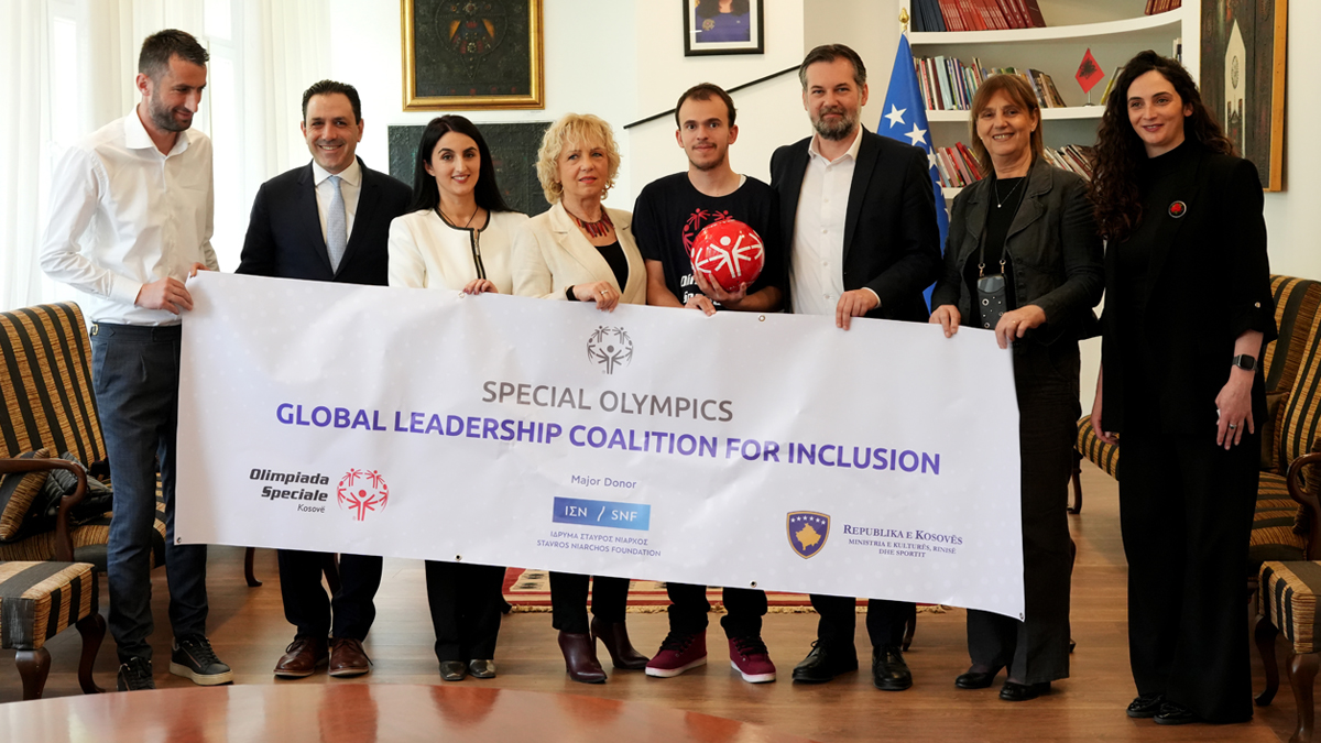 Group of people wearing formal clothing while holding a sign that says ‘Special Olympics Global Leadership Coalition for Inclusion’