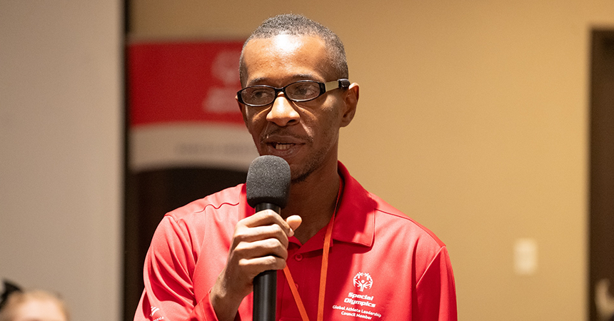 A man stands speaking into a microphone. 