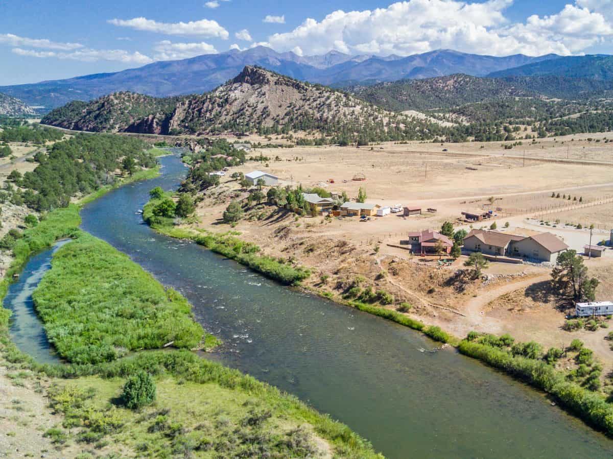 aerial photo of residential real estate property next to river with mountains in background in Howard, CO