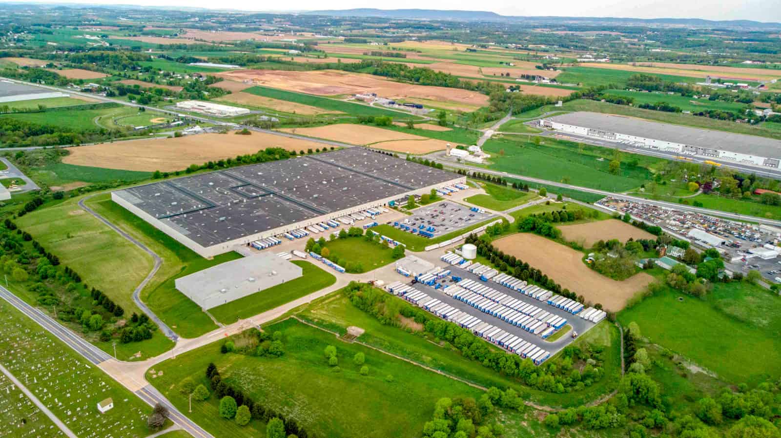 drone photo of shipping warehouse in Pennsylvania with lots of trucks and truck beds