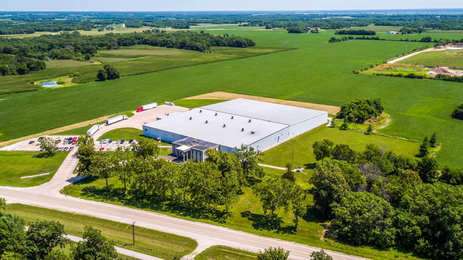 Shipping facility with 18-wheeler trucks and loading bays taken from drone in Iowa