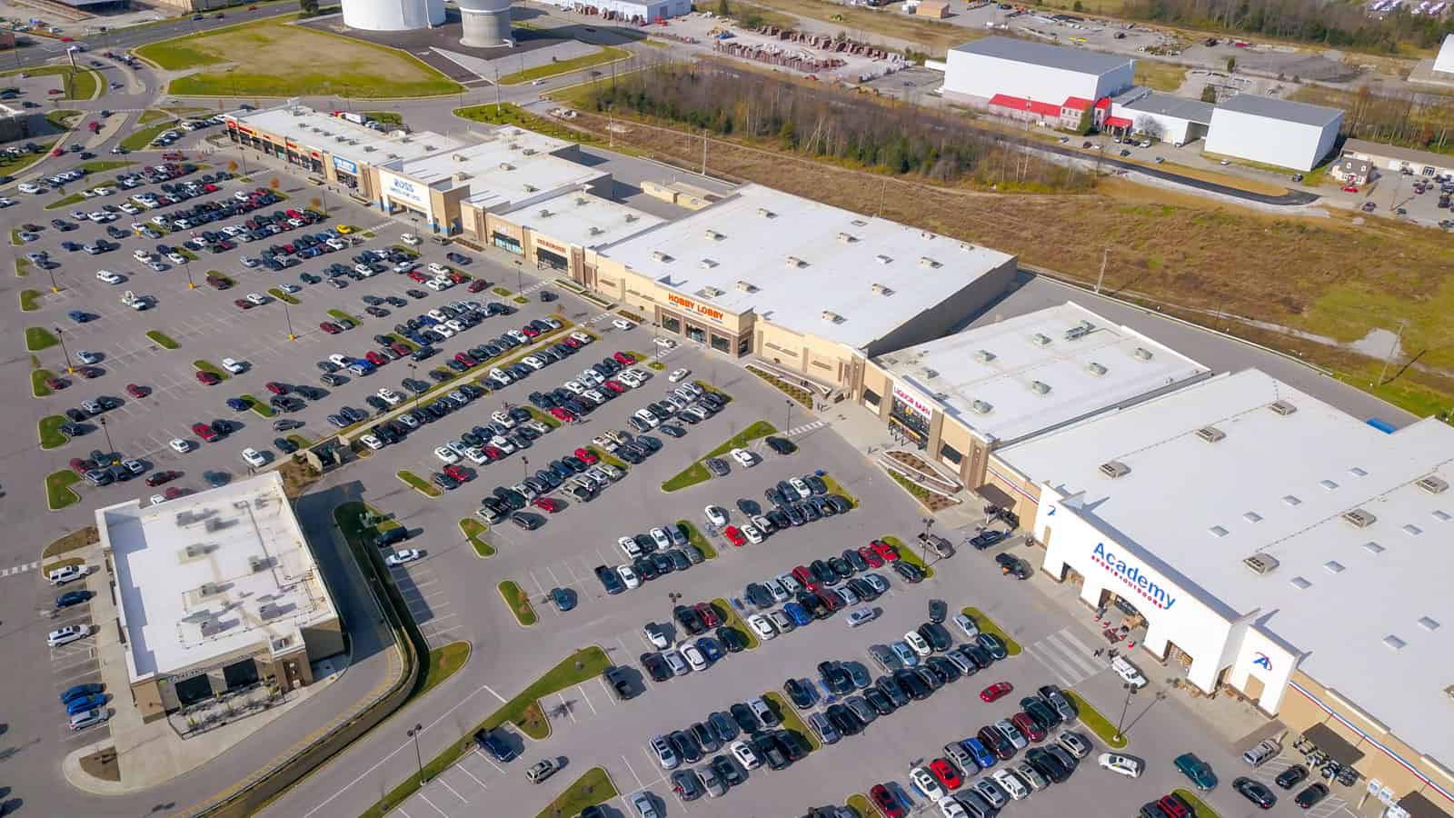 aerial drone photo of commercial real estate shopping plaza filled with cars in the parking lot