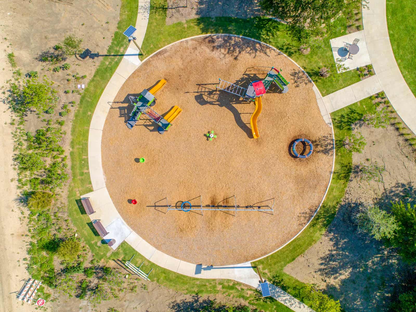 aerial drone photo looking down at a playground with a swing set, slides, and climbing structure