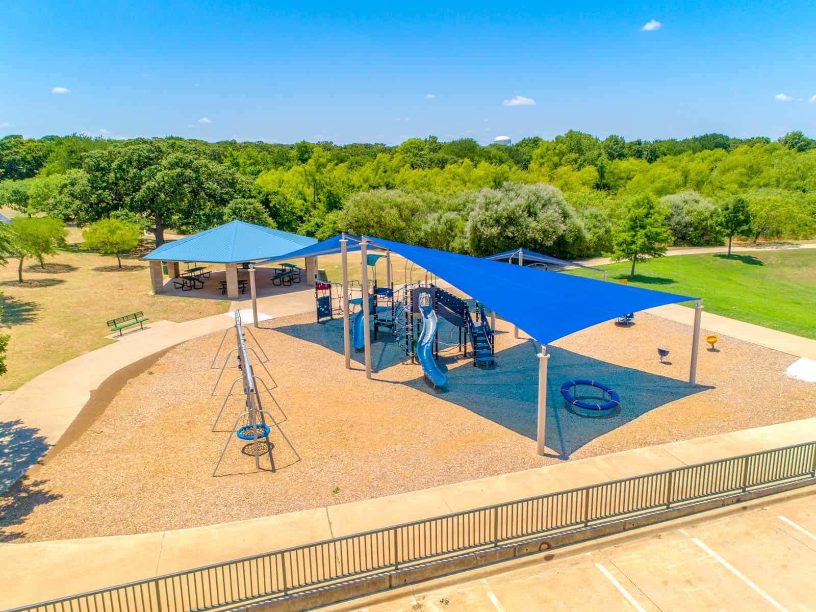 aerial drone photo of a playground with swings and slides covered by blue tarp