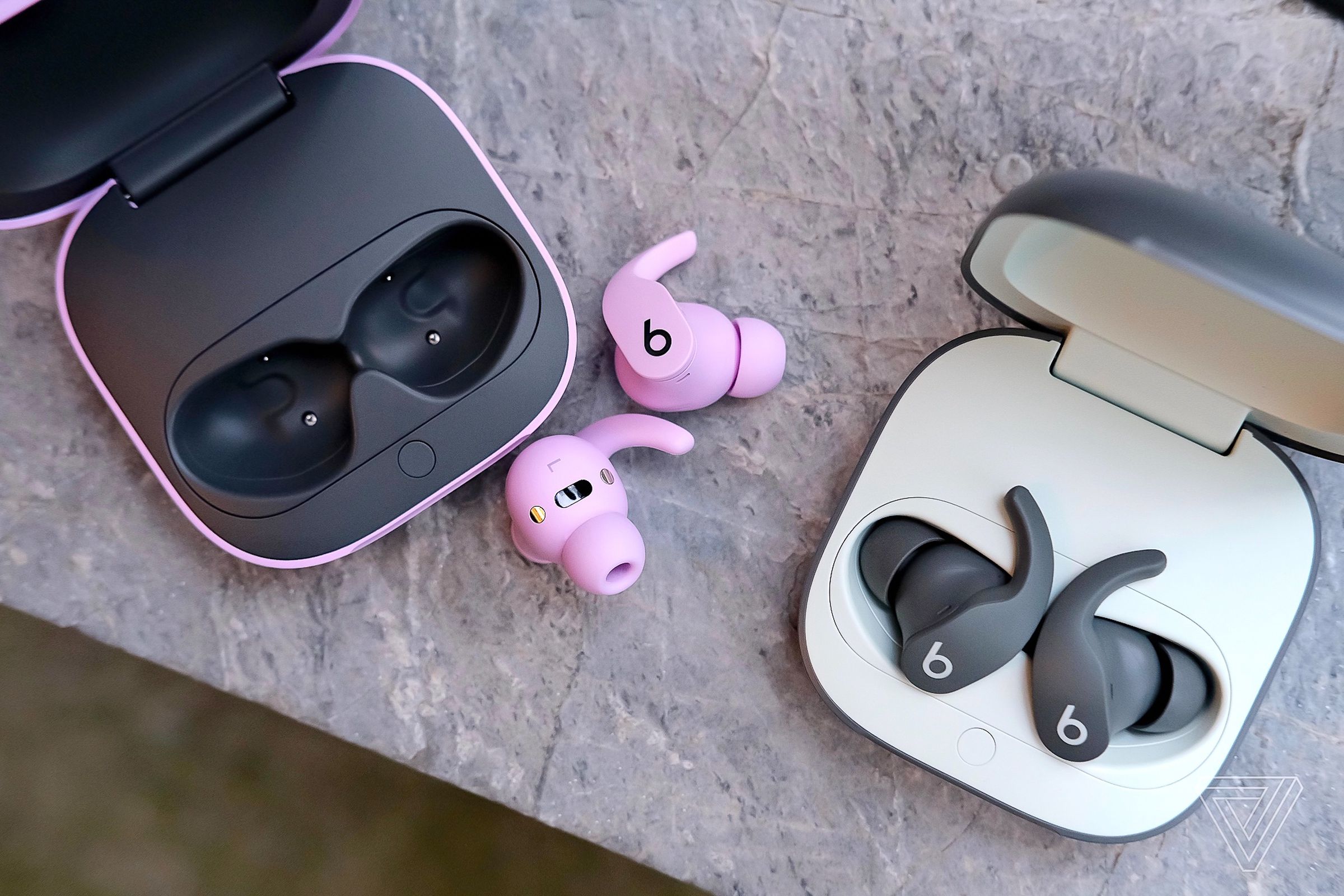 A photo of two pairs of Beats Fit Pro earbuds on a marble surface.