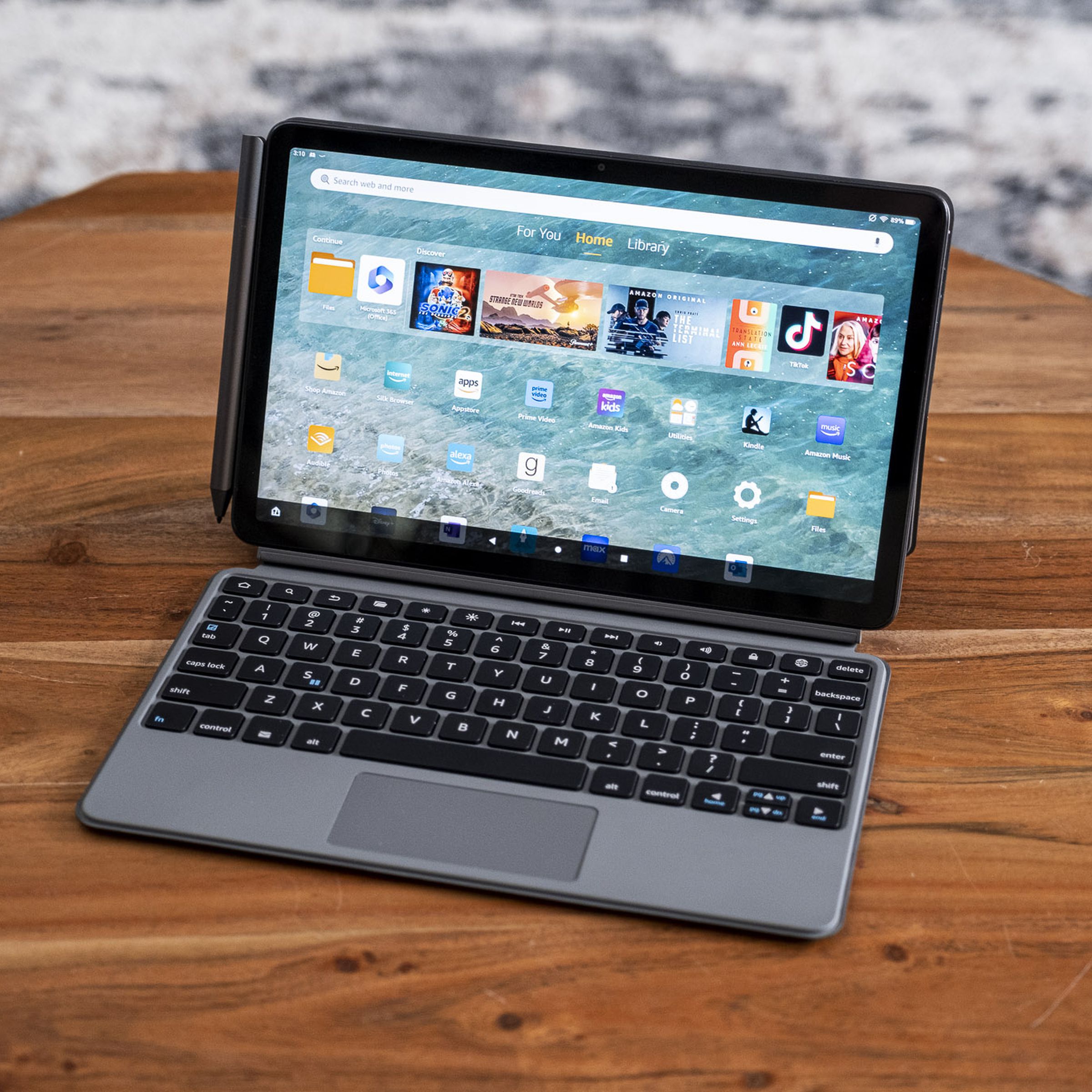 An Amazon Fire Max 11 tablet in its keyboard case on a wooden table.