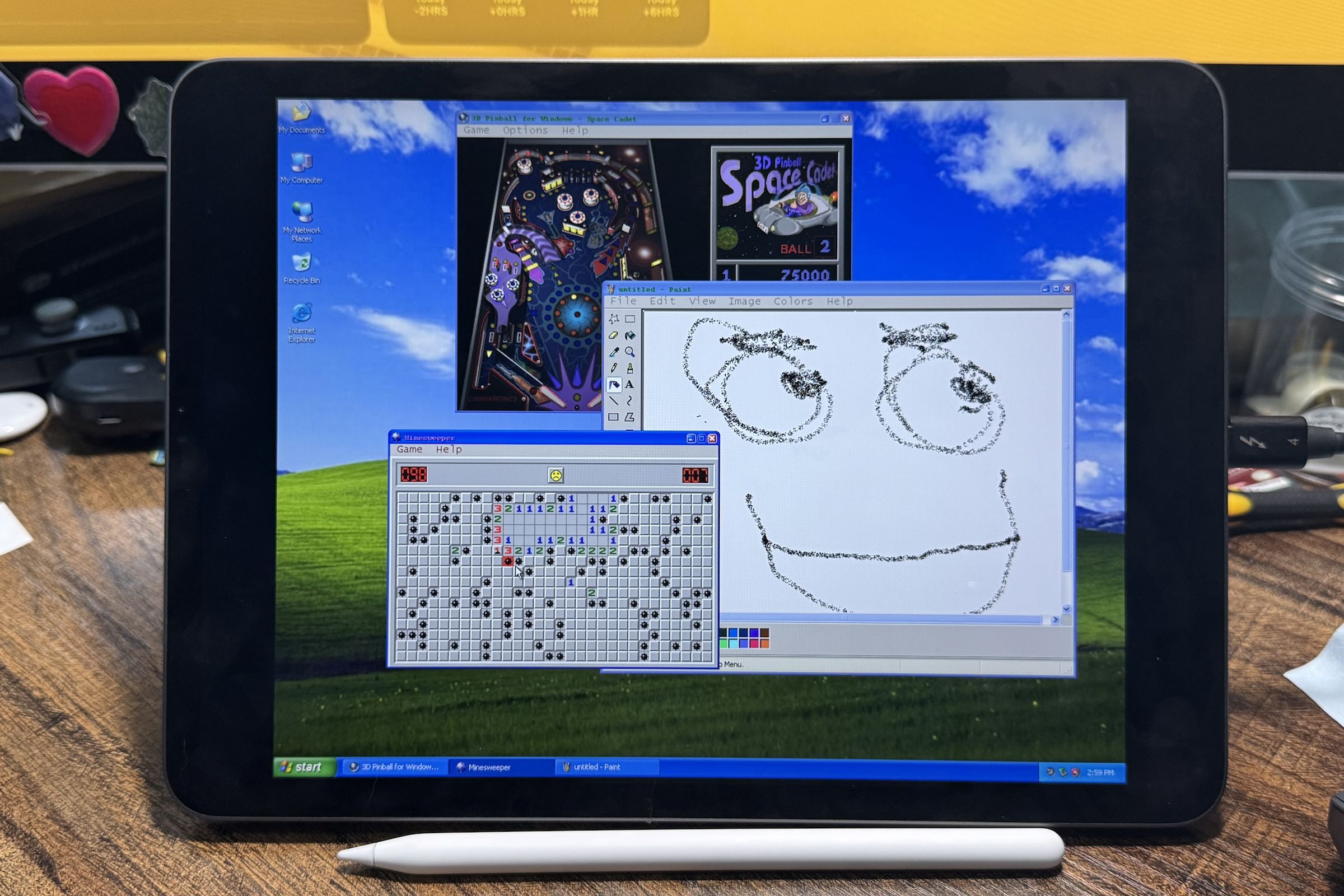 A picture of an iPad running Windows XP, with Minesweeper, 3D Pinball, and MS Paint on the screen.