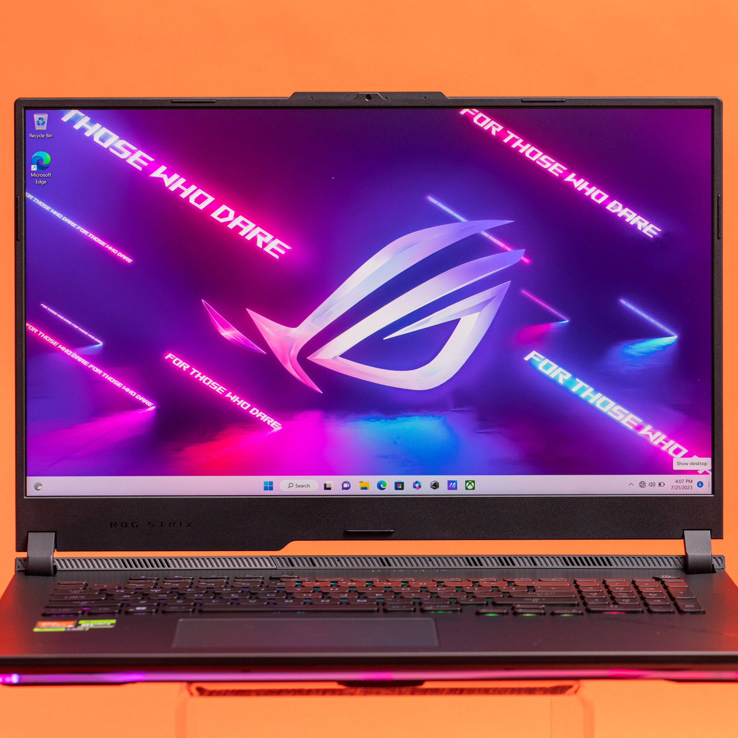 The Asus ROG Strix Scar 17 on an orange background displaying a desktop with the ROG Logo that reads “Hard Drive”.