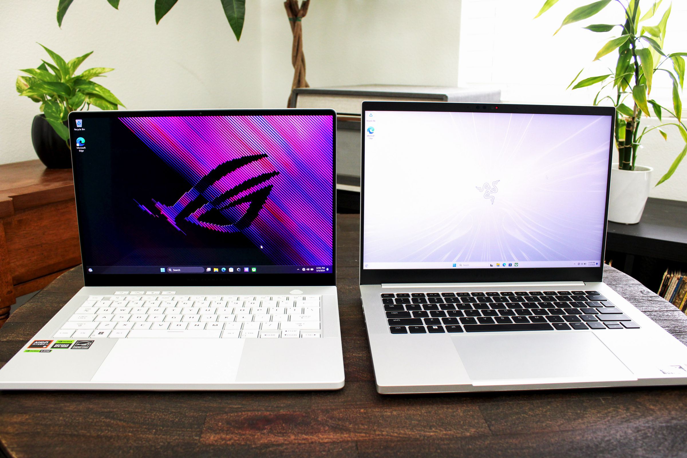 Two open and powered-on laptops on top of a dark wood table