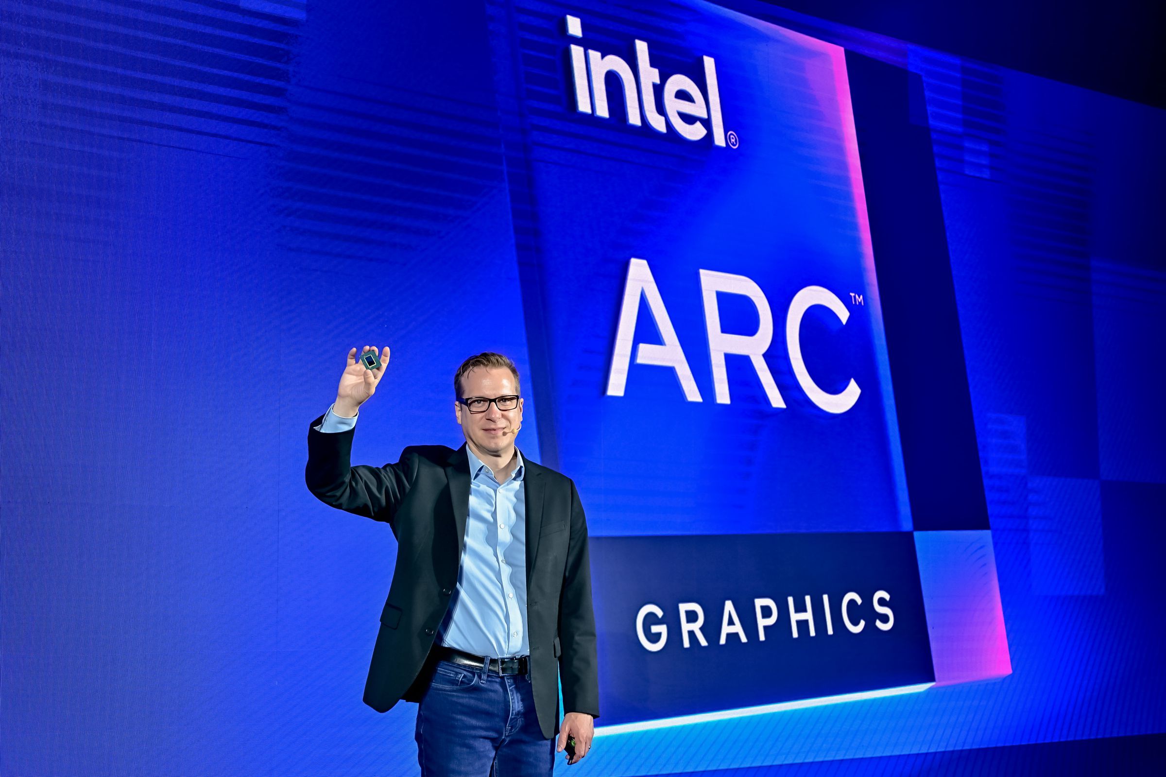 Intel exec Jack Weast holding a chip in front of an “Intel Arc Graphics” sign.