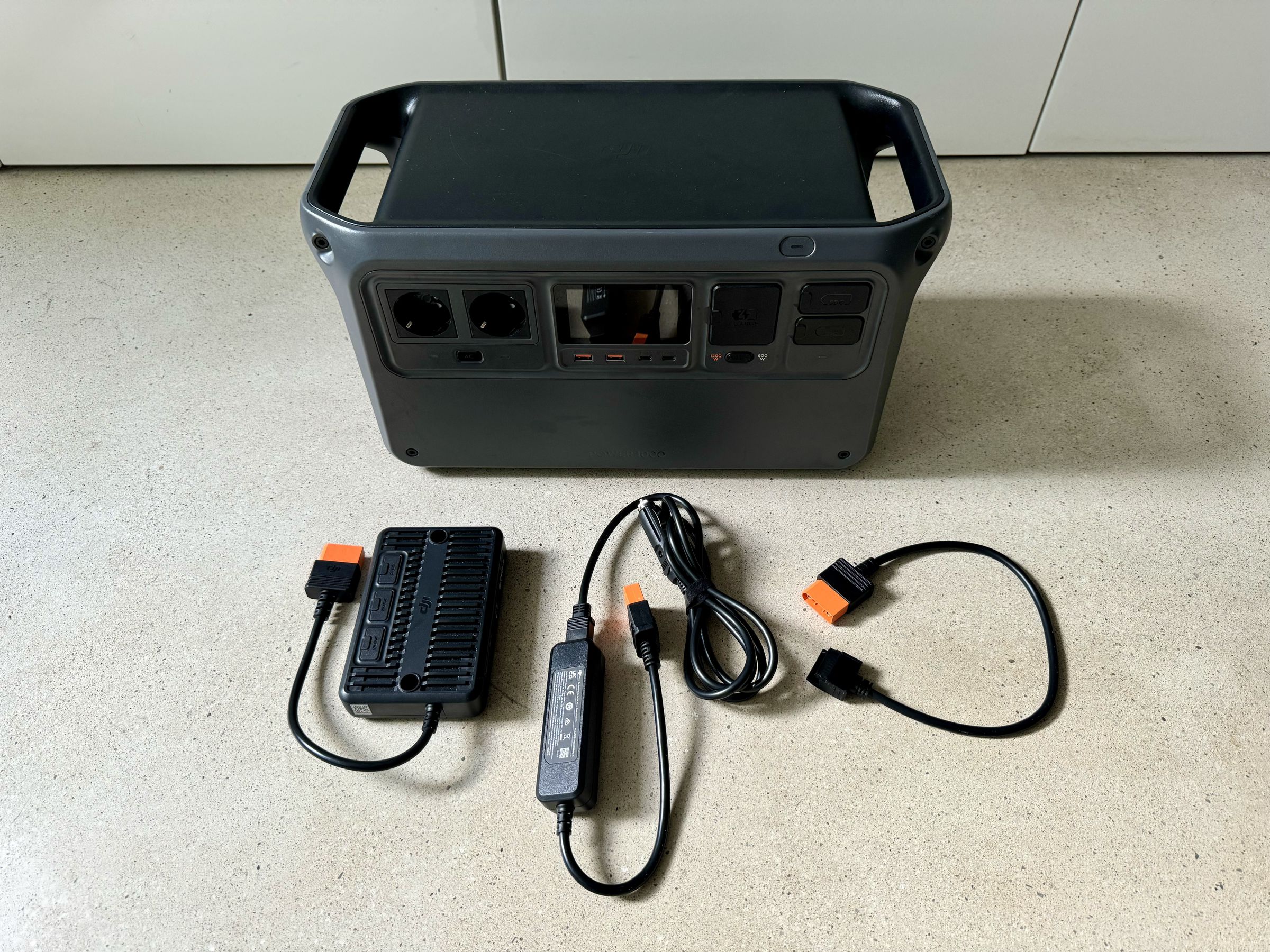 <em>The Power 1000 with three of DJI’s SDC adapters. From left to right, the MPPT controller for solar panels (minus the kit that mounts it to the power station), the 12V adapter to charge from your car’s cigarette lighter output, and the Air 3 battery charger.</em>