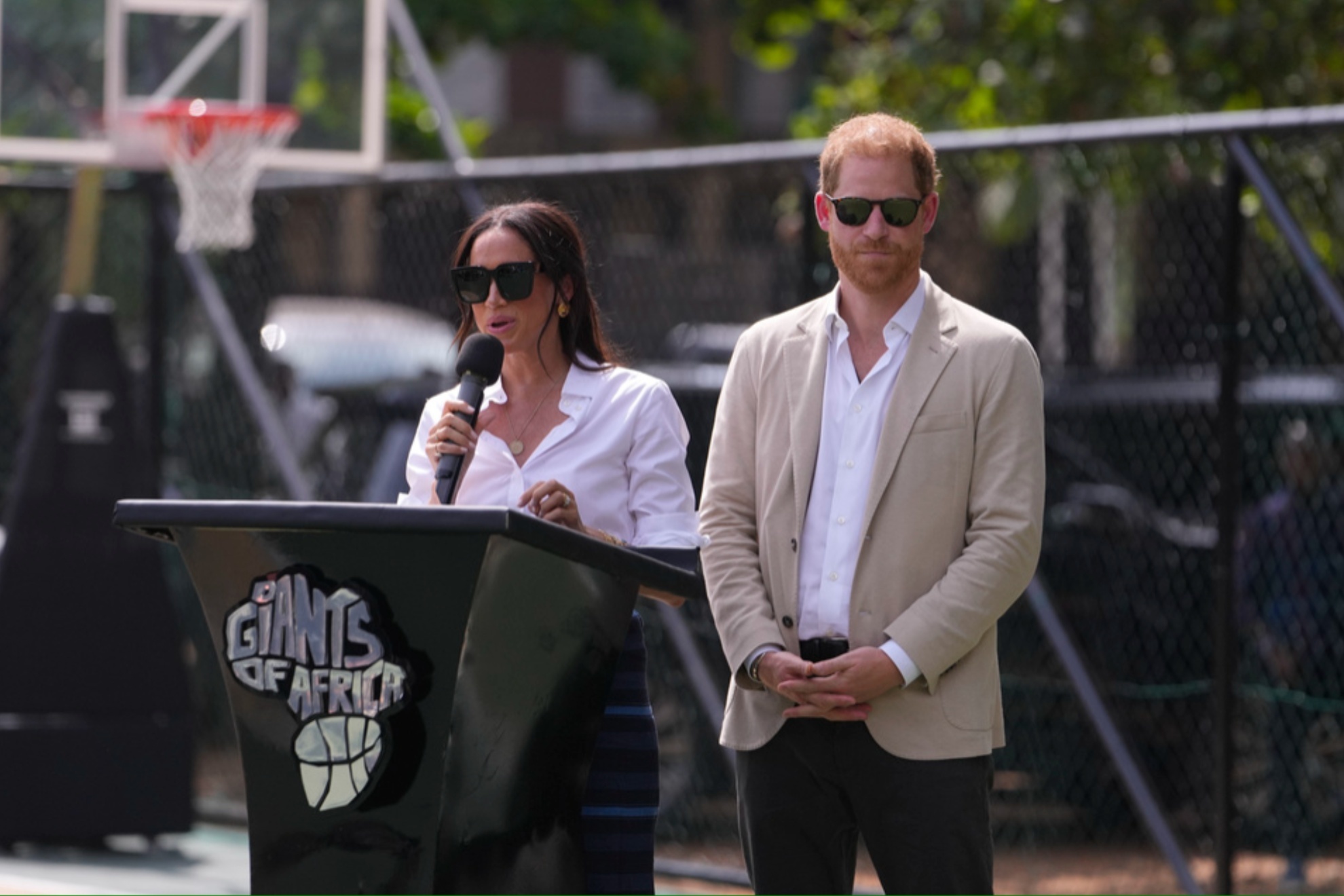 Meghan Markle speaks next to Prince Harry durin a Basketball clinic in Nigeria.
