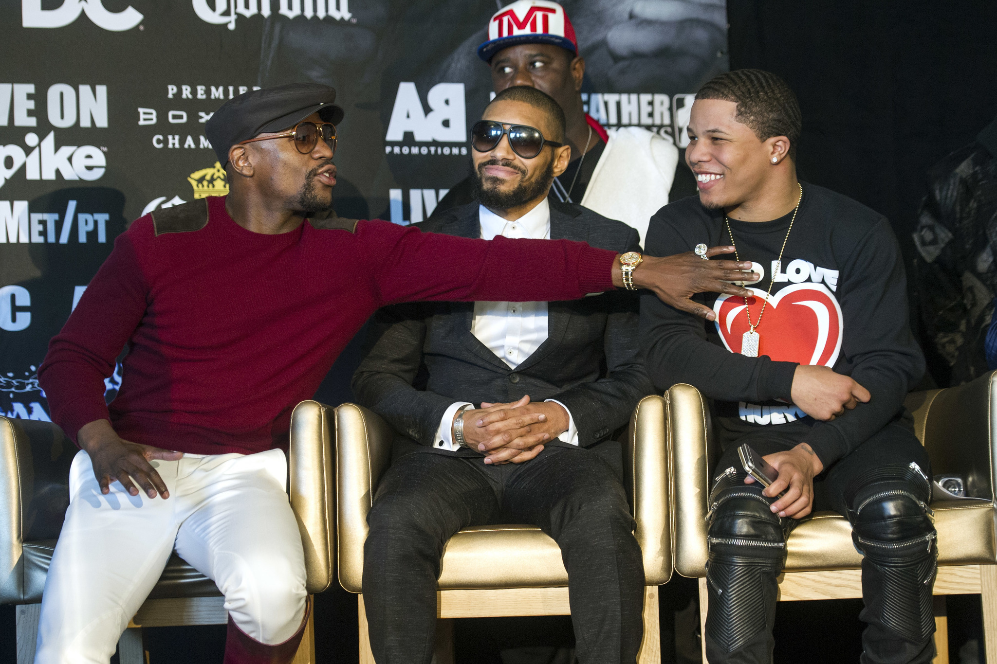 Floyd Mayweather, left, reaches over Ashley The Treasure Theophane, center, to pat Gervonta Davis on the chest