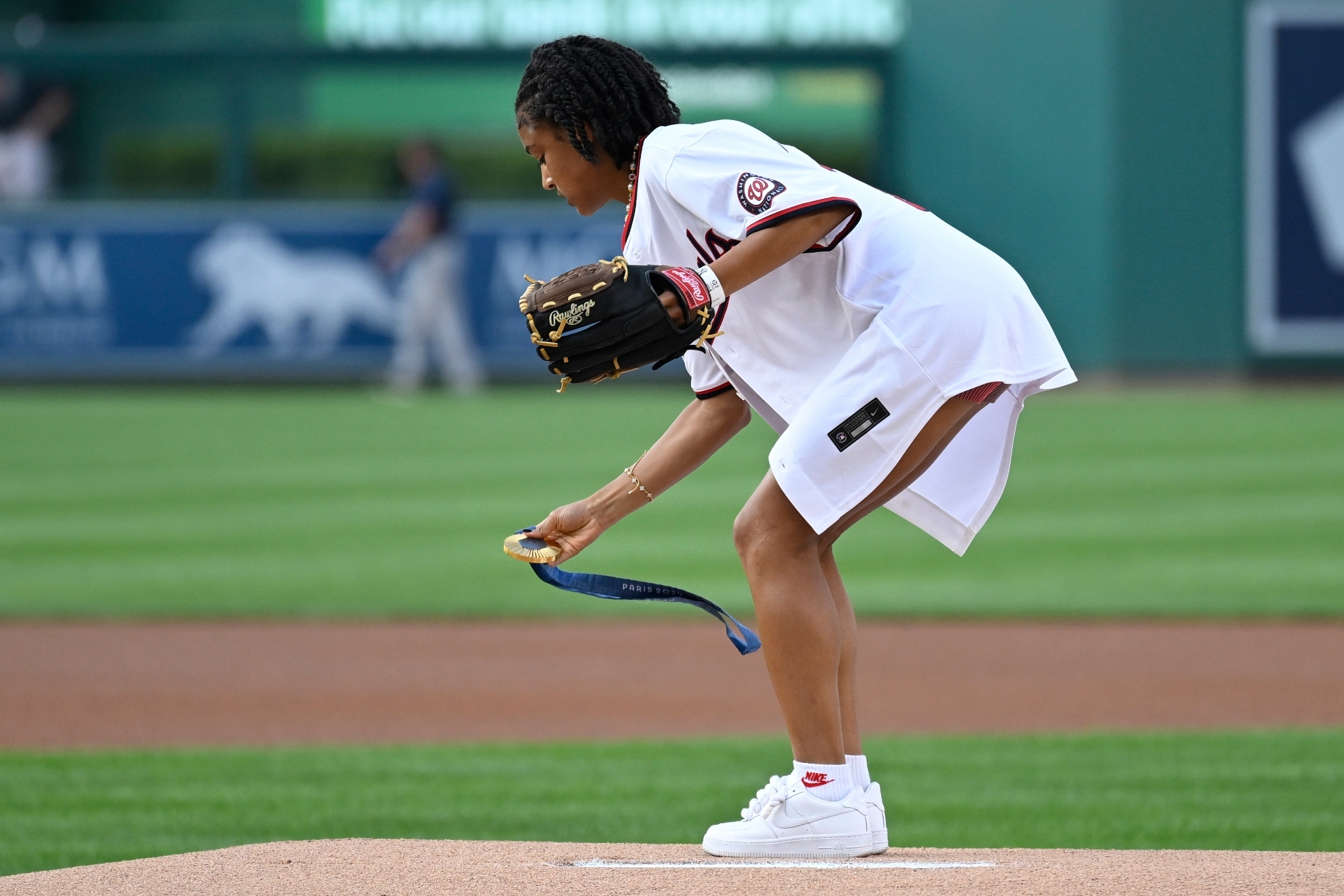 U.S. Olympic womens soccer team member Croix Bethune lays down her gold medal from the 2024 Paris Olympics on the pitchers mound so she can throw the opening pitch before a baseball game between the Washington Nationals and New York Yankees,