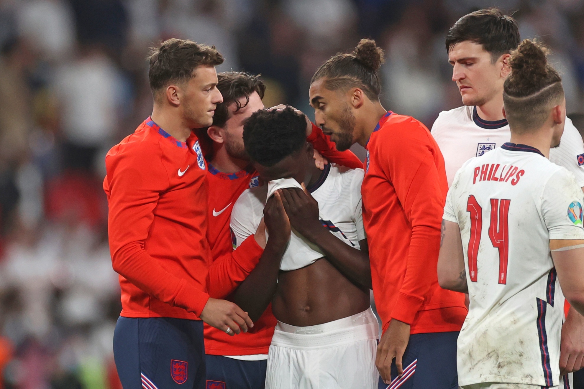 FILE - England players comfort teammate Bukayo Saka after he failed to score a penalty during a penalty shootout after extra time during of the Euro 2020 soccer championship final match between England and Italy at Wembley stadium in London, Sunday, July 11, 2021. Missing penalties in a major international soccer final was bad enough for three Black players, Marcus Rashford, Jadon Sancho and Bukayo Saka, who were on Englands national team. Being subjected to a torrent of racial abuse on social media in the aftermath made it even worse. Saka, who has more than 1 million followers on Twitter, remains on social media despite the abuse after Englands Euro 2020 loss. (Carl Recine/Pool Photo via AP, File)