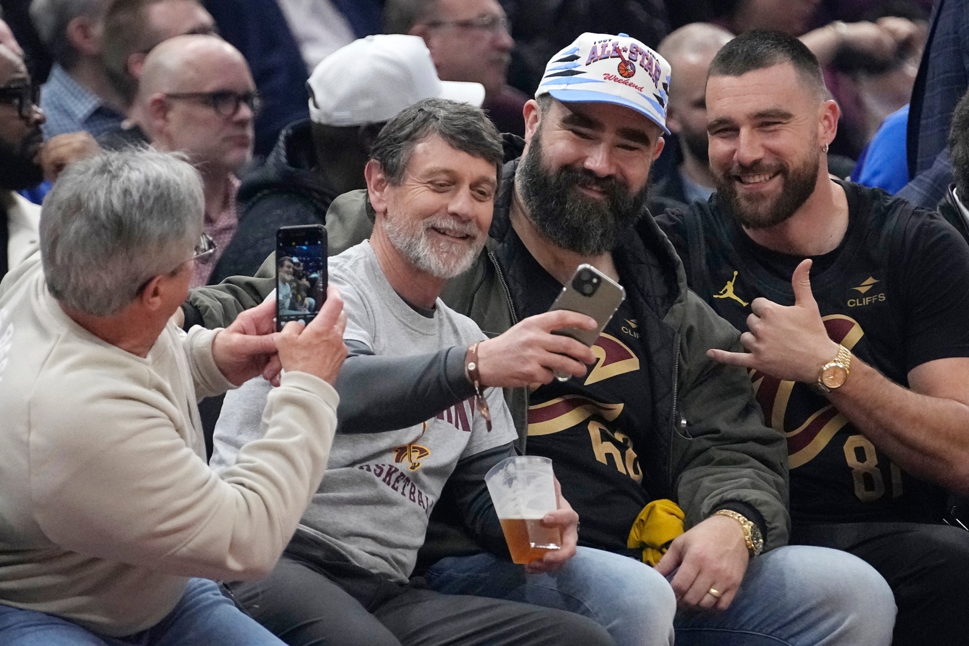 Jason Kelce, second from right, and Travis Kelce, right, pose for a photo with fans courtside at the Celtics-Cavaliers NBA basketball game, Tuesday, March 5, 2024, in Cleveland.