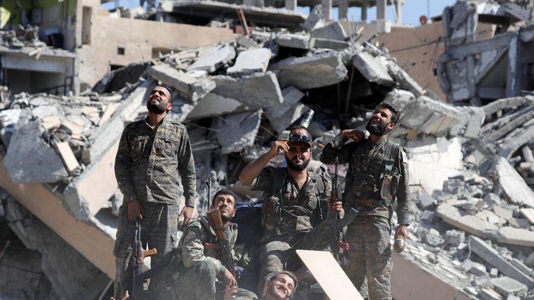 Fighters of Syrian Democratic Forces look up at a camera drone 