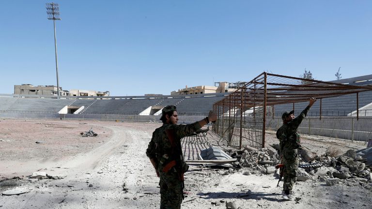 SDF fighters take a selfie at the stadium after it was retaken from the Islamic State militants, in Raqqa