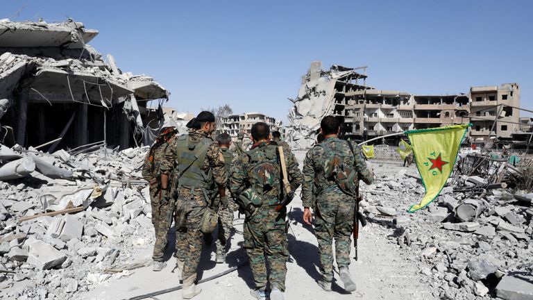 Fighters of Syrian Democratic Forces walk past the ruins of destroyed buildings near the National Hospital after Raqqa was liberated from the Islamic State militants