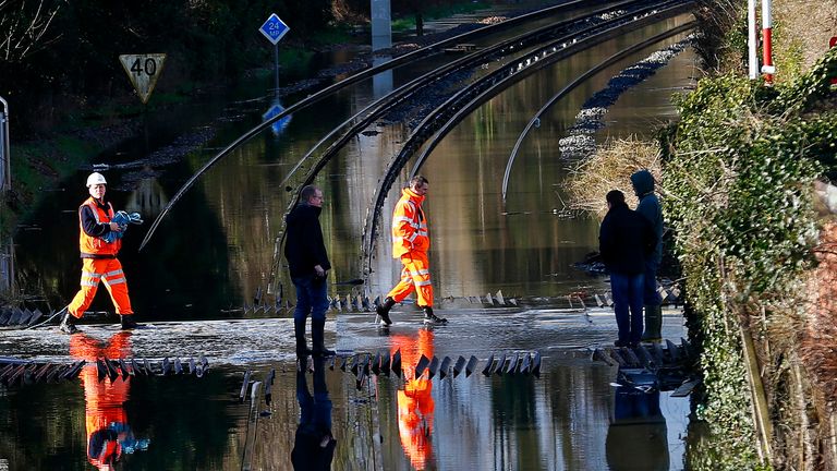 Railway workers are seen crossing the tracks after the river Thames flooded the railway in the village of Datchet, southern England February 10, 2014. REUTERS/Eddie Keogh (BRITAIN - Tags: DISASTER ENVIRONMENT)
