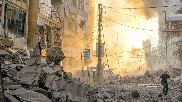 A man runs for cover as smoke rises in the background following an Israeli airstrike in Beirut, Lebanon. Pic: AP