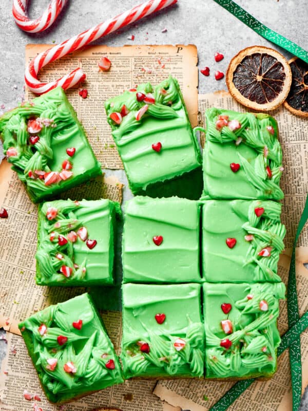 Twelve slices of grinch cake topped with candy on a counter.