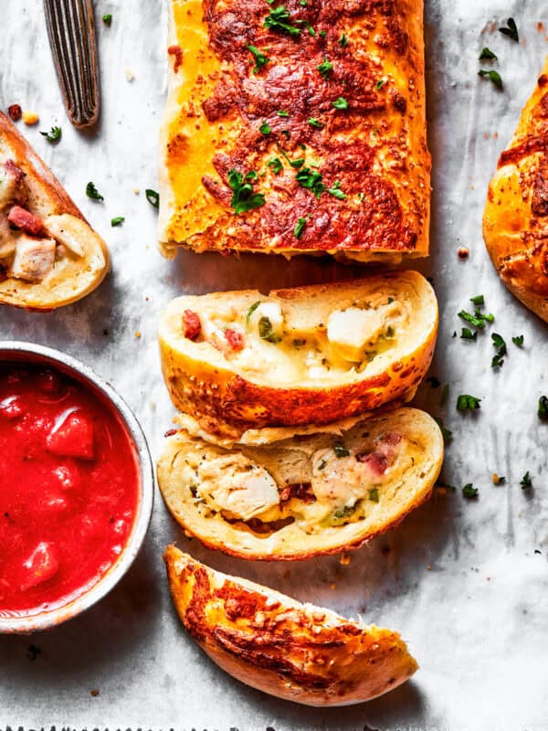 A sliced Costco chicken bake and a bowl of sauce.