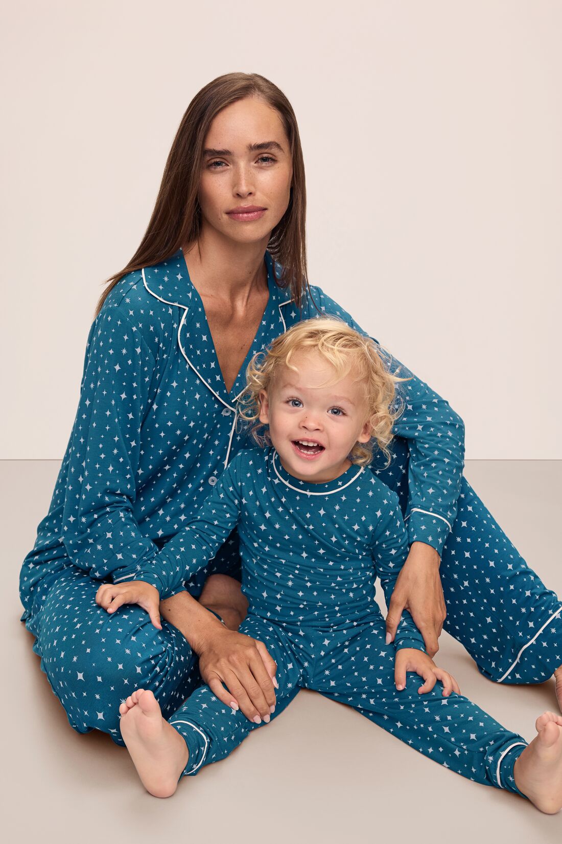 Model is wearing Kids Printed TENCEL™ Modal Unisex Long PJ Set in Festive Lights Sapphire/Ivory.