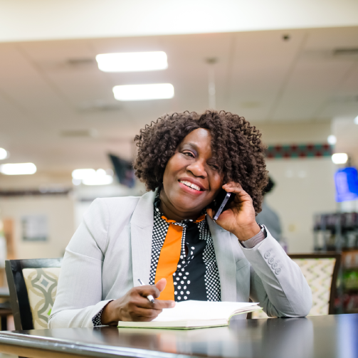 A woman sitting at a table, engaged in a phone conversation