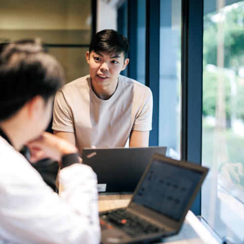 A man sitting at a table, working on a laptop