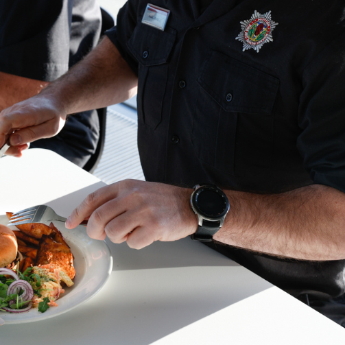 Hands of a man wearing a black uniform, eating a meal