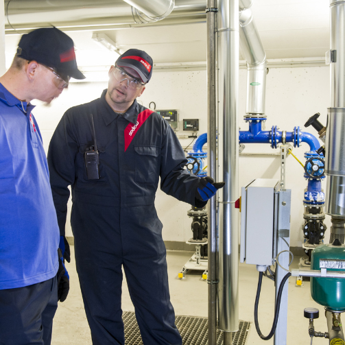 A man in blue overalls standing and explaining a technical problem to a man in a blue uniform. 