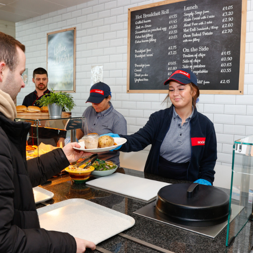 A woman in uniform serving food to a customer